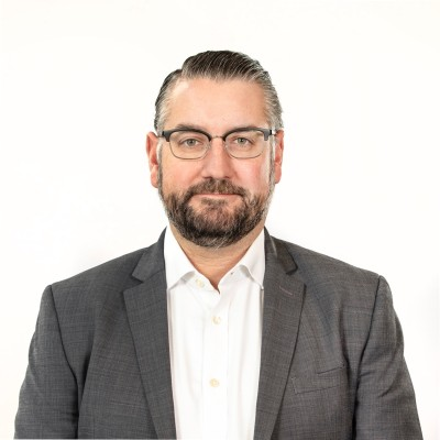 Portrait of a person in a gray suit and white shirt against a white background